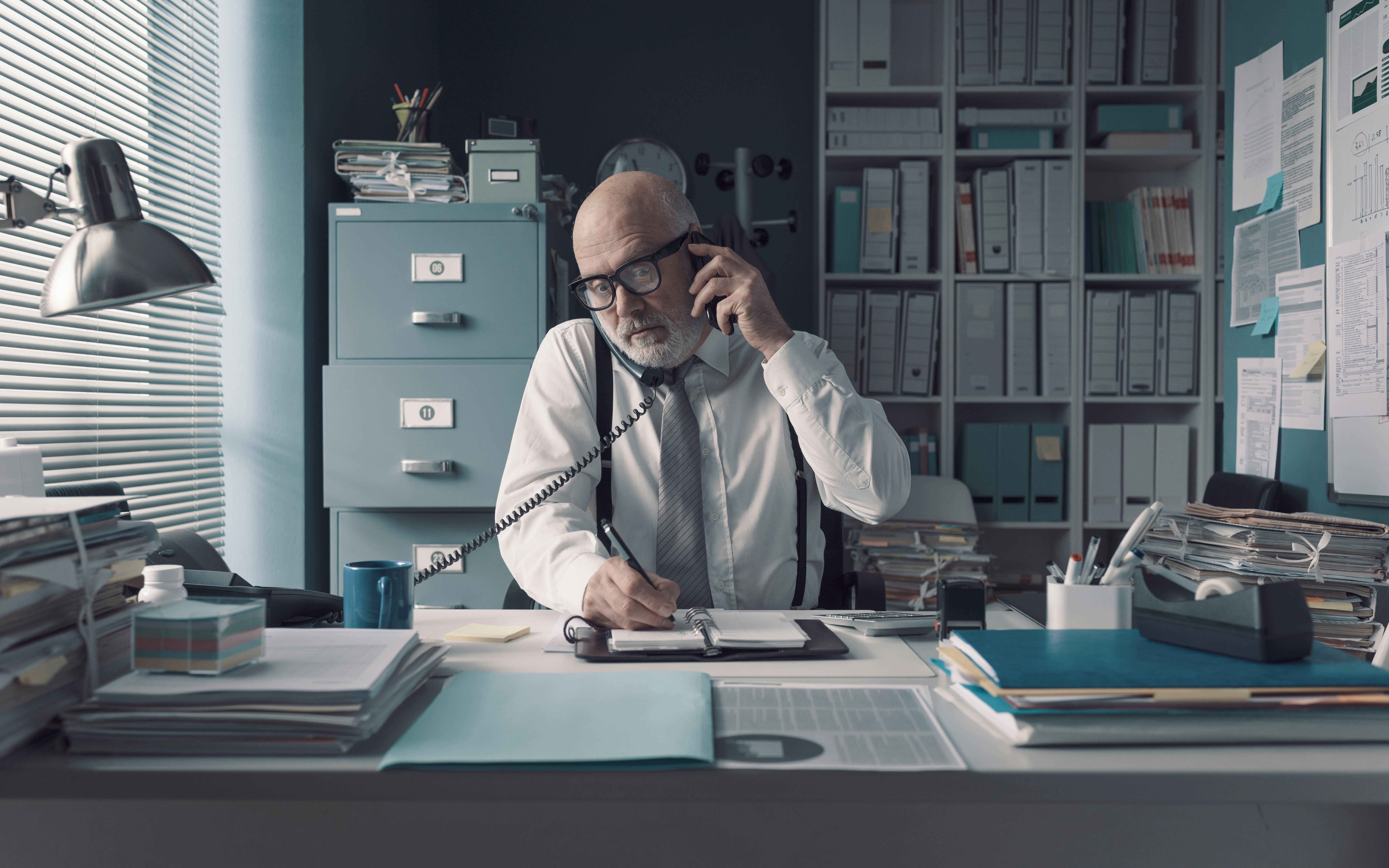A professional having a phone conversation while taking notes
